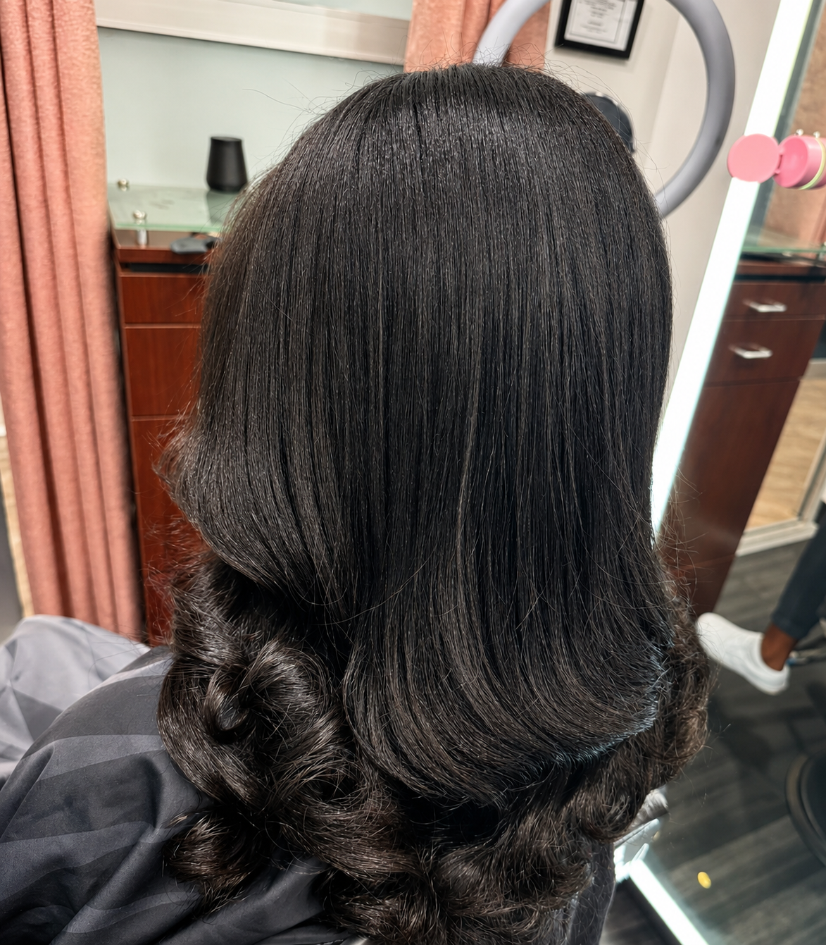 Glossy black silk press with soft curled ends from behind